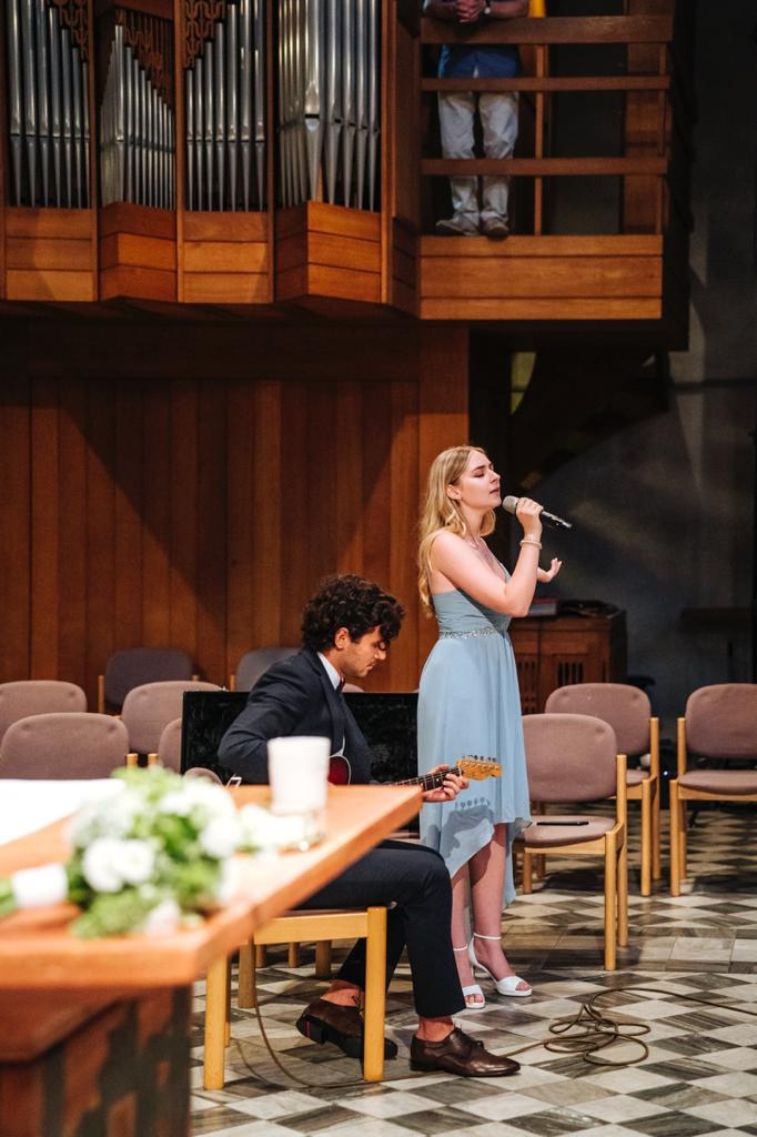 Maya singt in einer Kirche, begleitet von einem Gitarristen