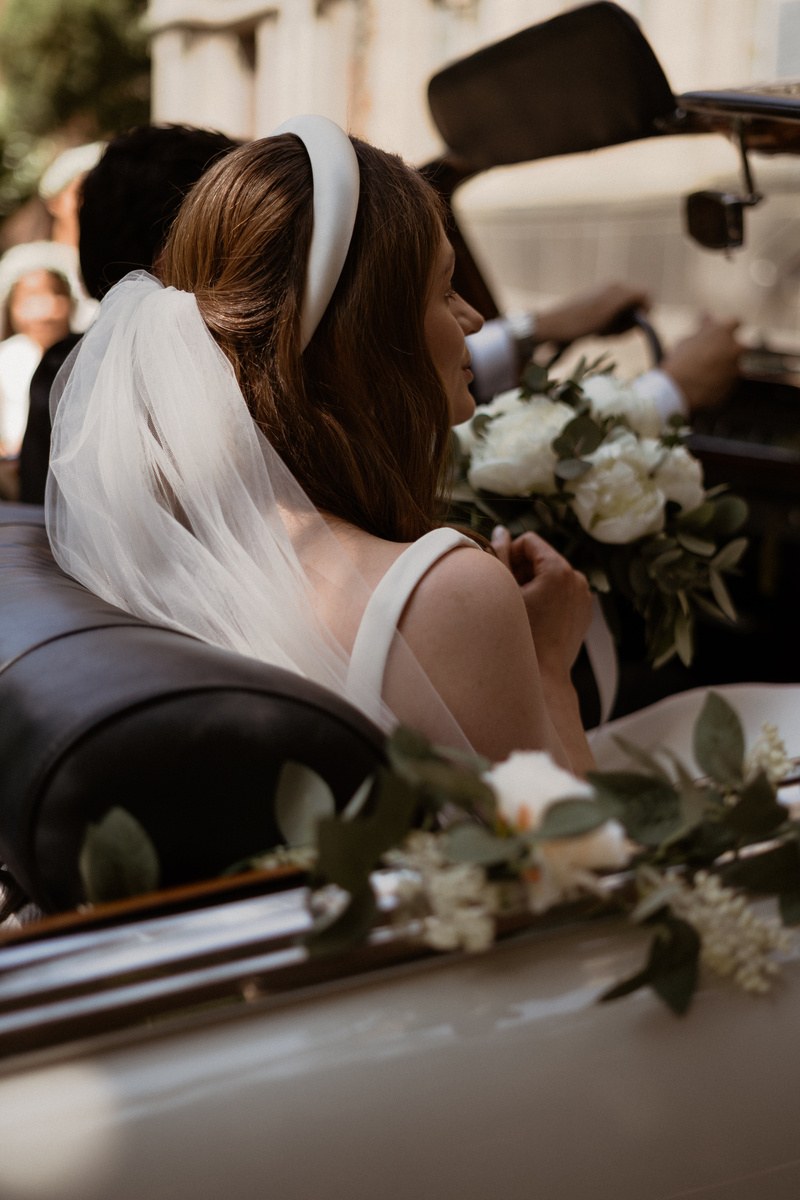 Braut mit Schleier sitzt in einem Hochzeitsauto